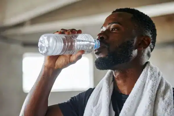 Image of man drinking water to improve hydration Ashford after work out.